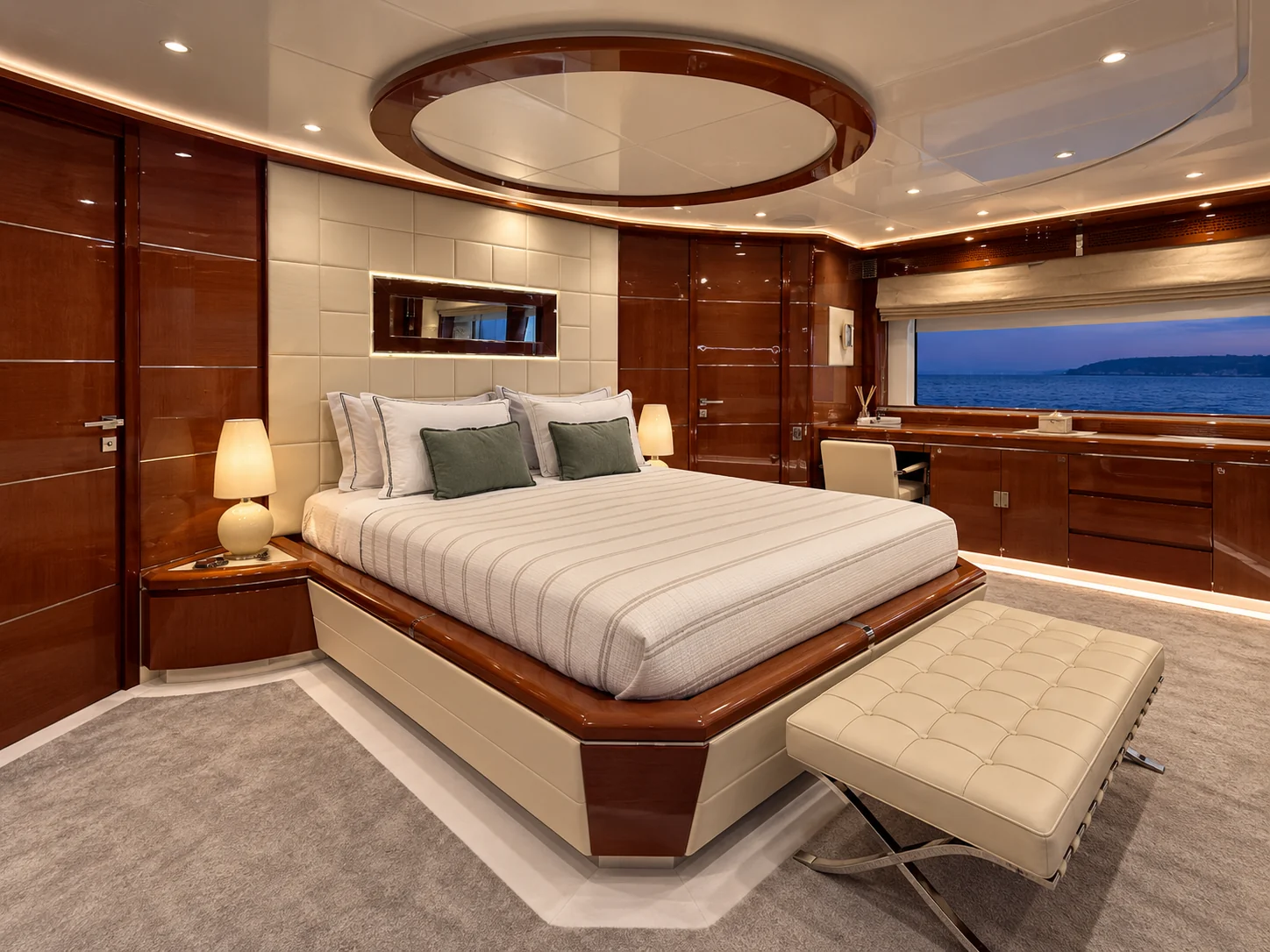 Owner's suite with a central bed beneath an oval ceiling detail and a desk under a wide window